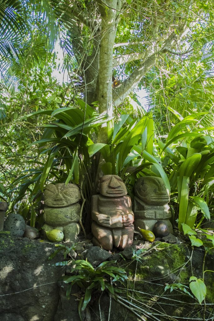tiki stone sculptures near a palm tree